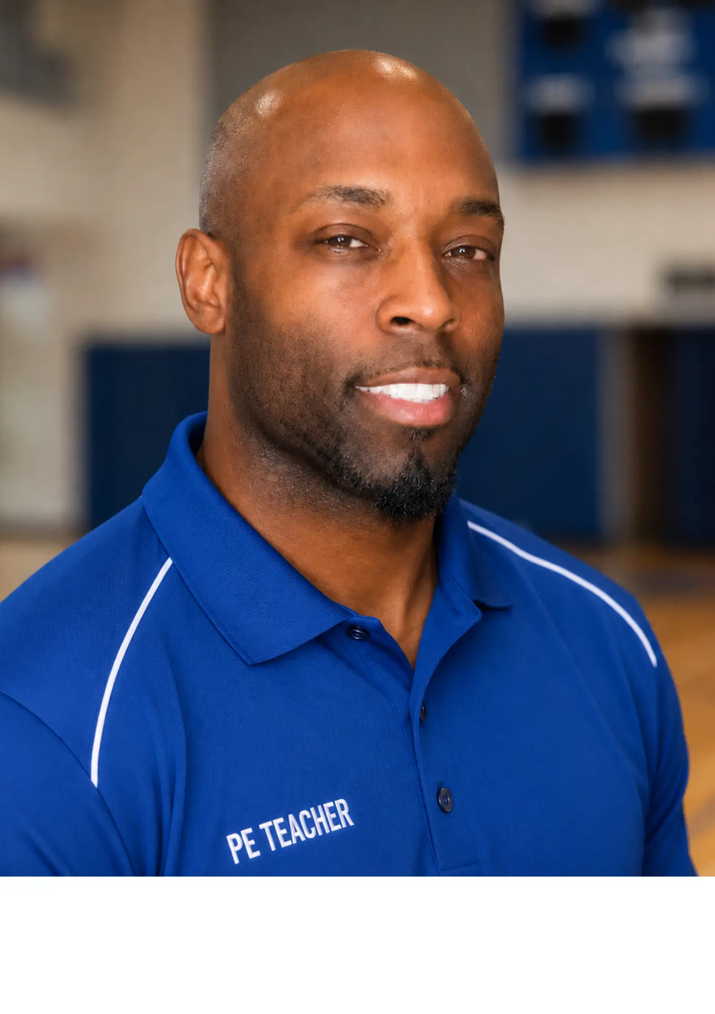 Close-up portrait of a smiling Black man in a blue polo shirt, likely a PE teacher, standing in a gymnasium setting.