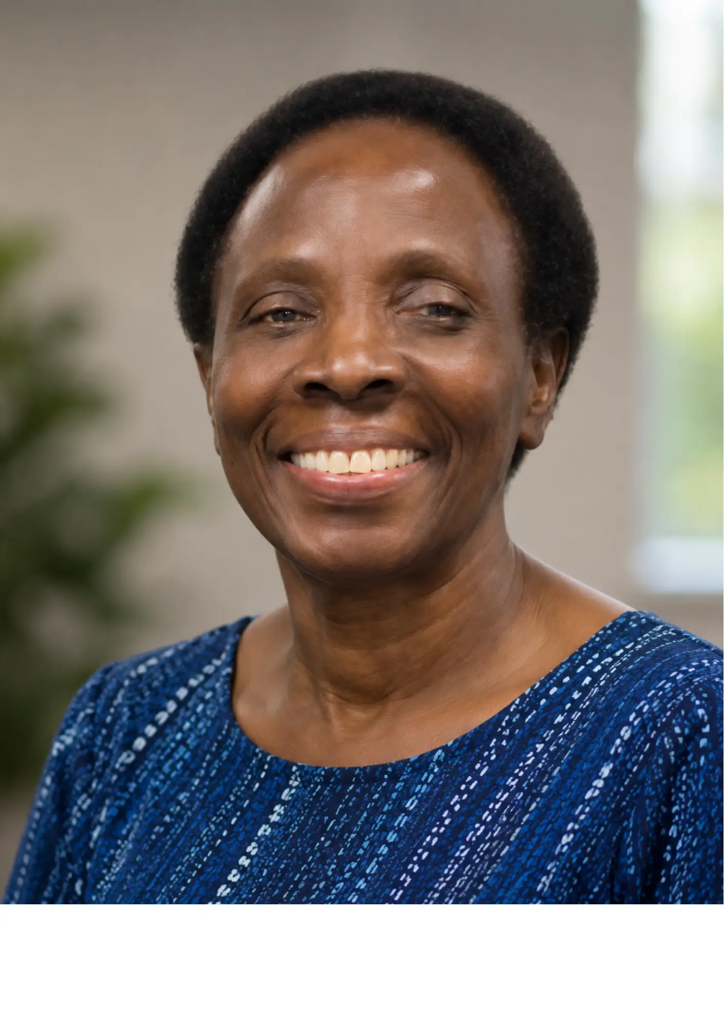 Close-up of a smiling woman with short natural hair wearing a blue patterned top